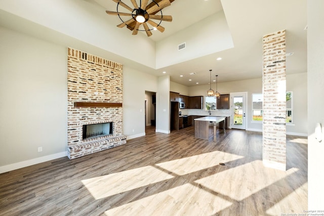 living room featuring sink, hardwood / wood-style flooring, ceiling fan, a towering ceiling, and a fireplace