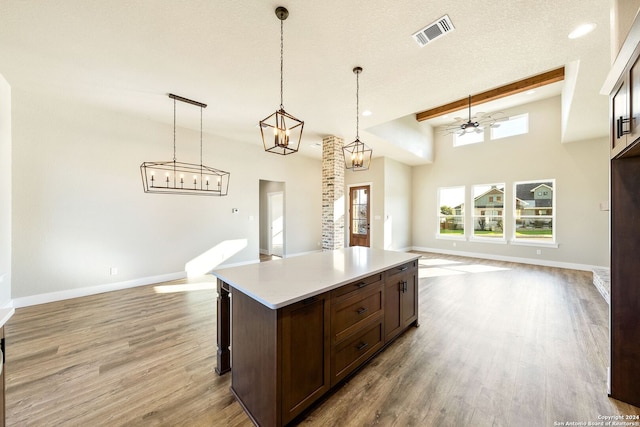 kitchen featuring dark brown cabinetry, ceiling fan, beamed ceiling, light hardwood / wood-style floors, and decorative light fixtures