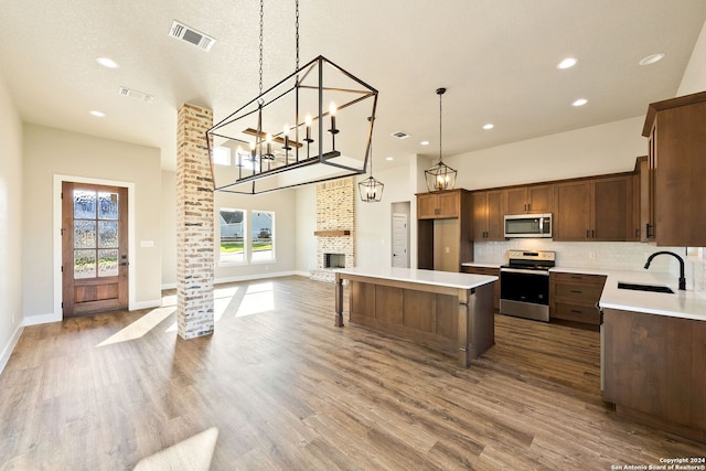 kitchen featuring sink, tasteful backsplash, decorative light fixtures, a kitchen island, and stainless steel appliances