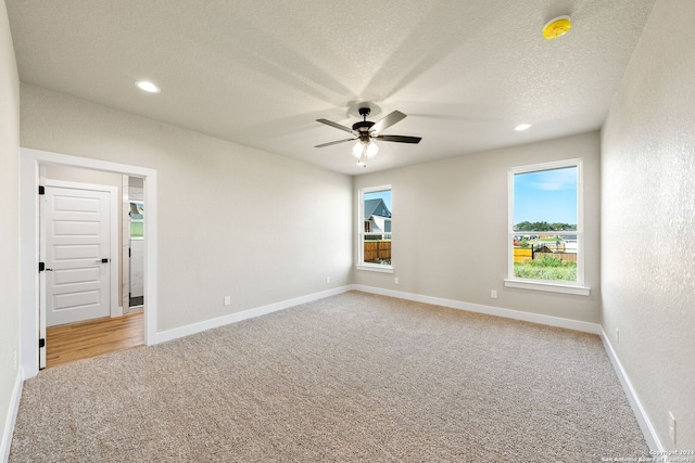 unfurnished room with carpet, a textured ceiling, ceiling fan, and a healthy amount of sunlight