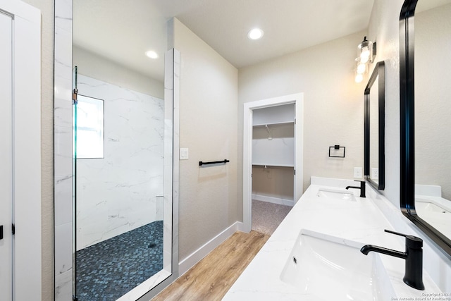 bathroom with a tile shower, vanity, and wood-type flooring