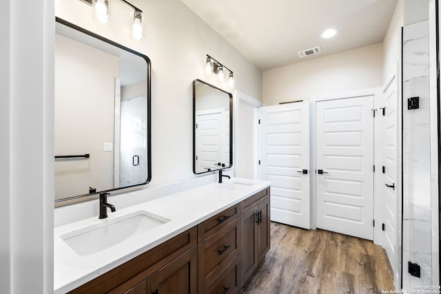 bathroom with hardwood / wood-style floors, vanity, and a shower with shower door