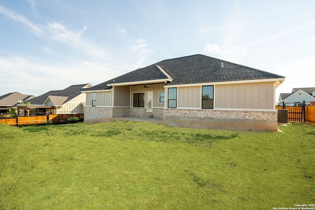 rear view of property featuring central AC and a lawn