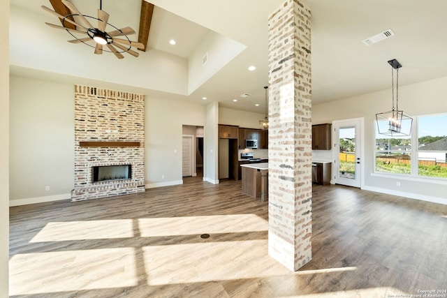 unfurnished living room featuring decorative columns, ceiling fan, beamed ceiling, and a high ceiling