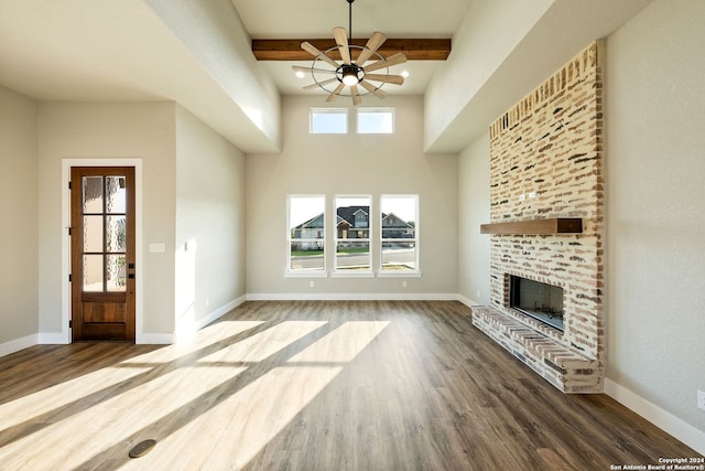 unfurnished living room featuring ceiling fan, plenty of natural light, beamed ceiling, and wood-type flooring