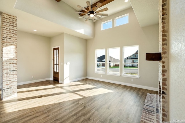 unfurnished living room with plenty of natural light, ceiling fan, a high ceiling, and light hardwood / wood-style flooring