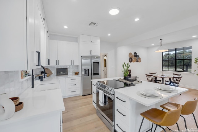 kitchen featuring white cabinetry, a center island, sink, stainless steel appliances, and pendant lighting