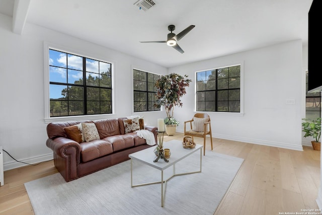 living room with beamed ceiling, light hardwood / wood-style flooring, and ceiling fan