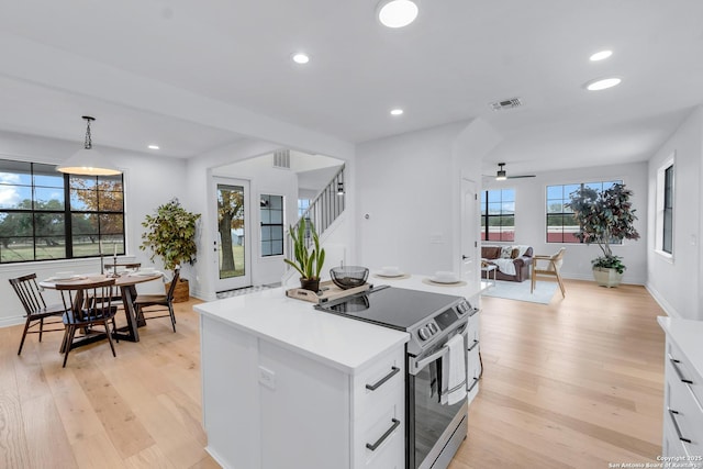 kitchen featuring white cabinetry, ceiling fan, light hardwood / wood-style flooring, pendant lighting, and stainless steel range with electric cooktop