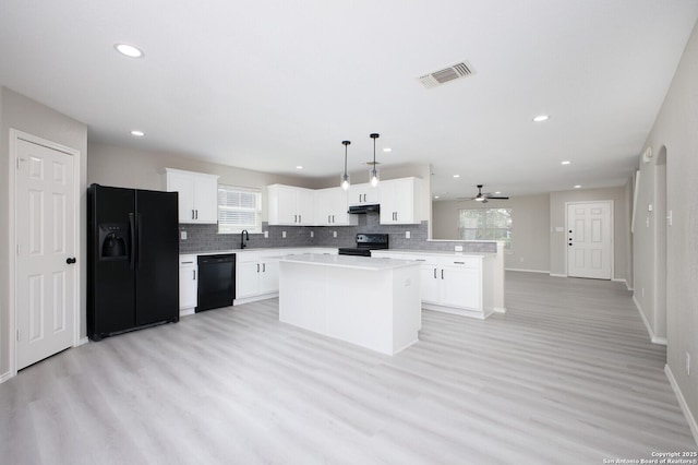 kitchen featuring ceiling fan, sink, black appliances, decorative light fixtures, and a kitchen island