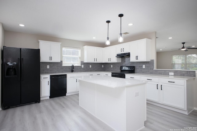 kitchen featuring ceiling fan, black appliances, decorative light fixtures, a center island, and white cabinetry