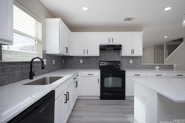 kitchen with sink, white cabinetry, light stone counters, and black appliances