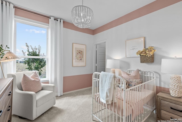 bedroom with a notable chandelier, a crib, and light carpet