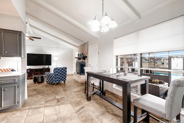 dining space with a fireplace, lofted ceiling with beams, and ceiling fan with notable chandelier