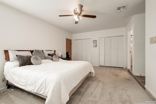 carpeted bedroom featuring ceiling fan and multiple closets