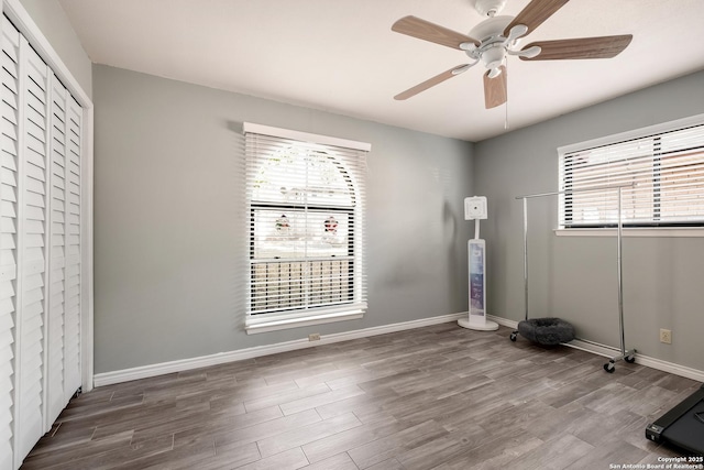 interior space featuring multiple windows, wood-type flooring, and ceiling fan