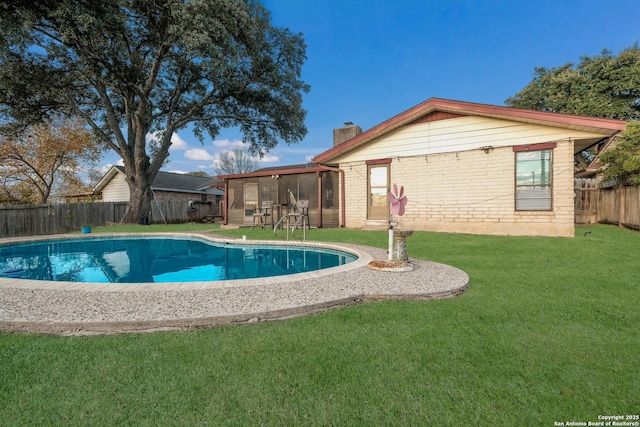 view of swimming pool featuring a lawn and a sunroom