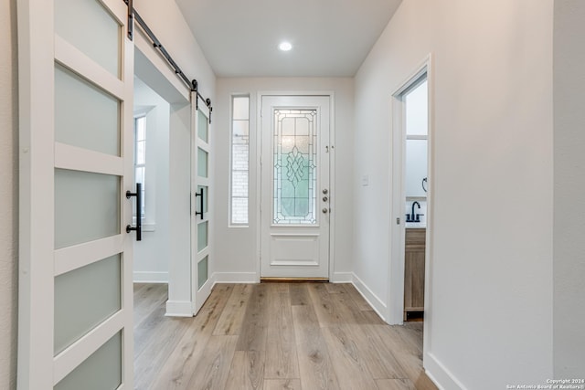 foyer entrance featuring a barn door and light hardwood / wood-style flooring