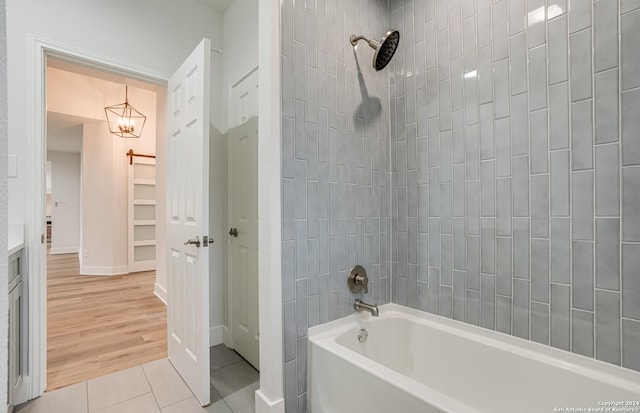 bathroom featuring tile patterned floors, a notable chandelier, and shower / washtub combination