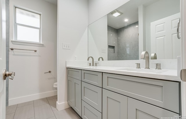 bathroom with a tile shower, tile patterned flooring, vanity, and toilet