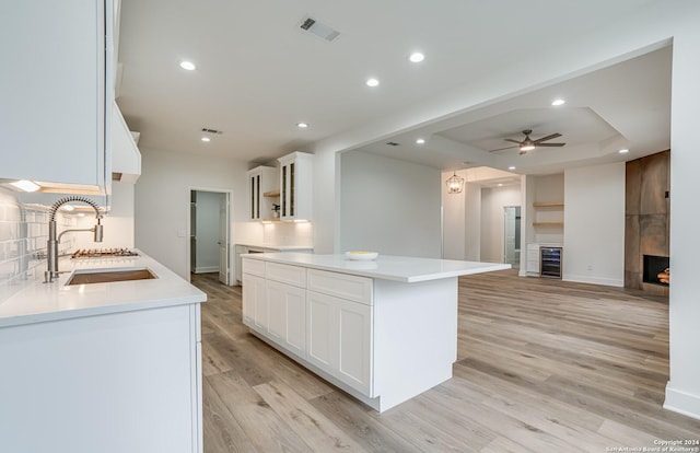 kitchen with white cabinets, a center island, a tray ceiling, and sink