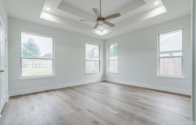 unfurnished room featuring a tray ceiling, ceiling fan, and light hardwood / wood-style floors