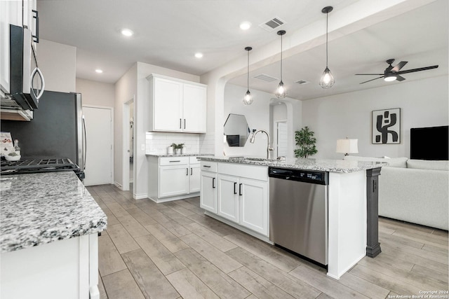 kitchen featuring a kitchen island with sink, white cabinetry, hanging light fixtures, and appliances with stainless steel finishes