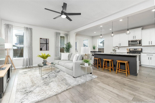 living room with ceiling fan, sink, and light hardwood / wood-style floors