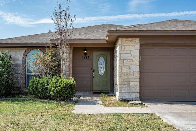 doorway to property with a garage and a yard