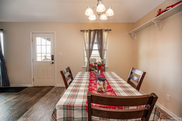 dining room with dark hardwood / wood-style floors and an inviting chandelier