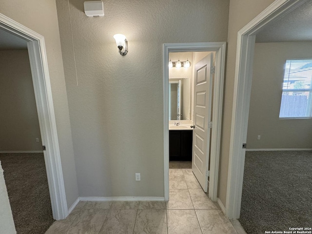 corridor with light colored carpet and sink