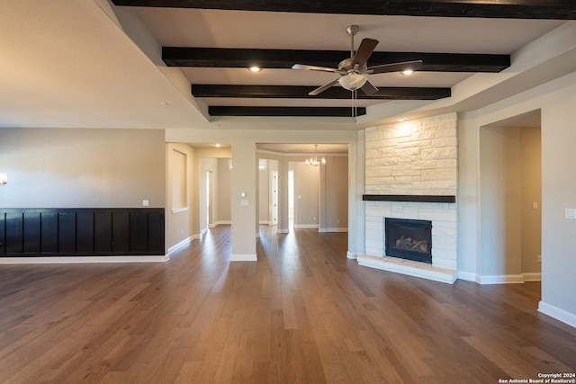 unfurnished living room featuring beamed ceiling, ceiling fan with notable chandelier, a fireplace, and hardwood / wood-style floors