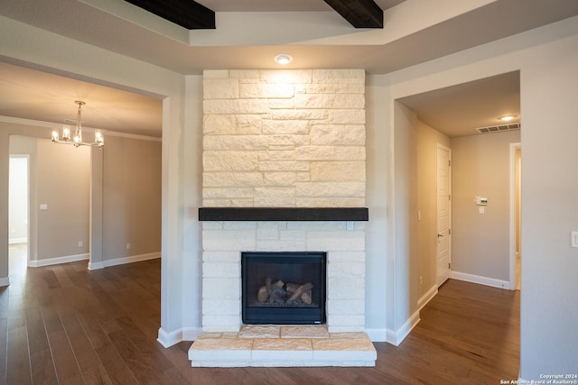 unfurnished living room with hardwood / wood-style floors, a stone fireplace, ornamental molding, a notable chandelier, and beam ceiling