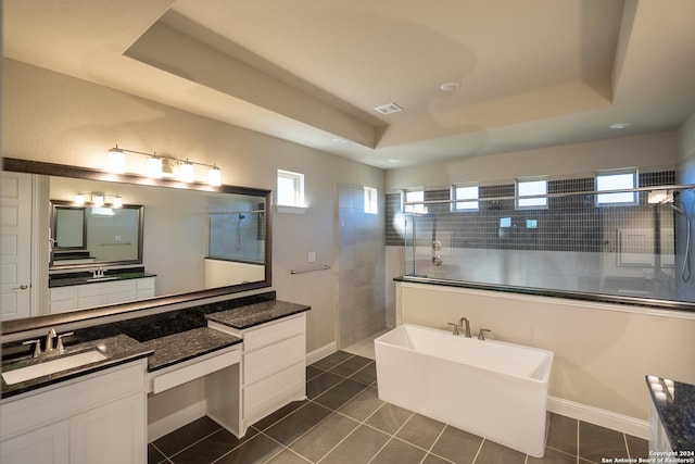 bathroom featuring tile patterned flooring, vanity, a raised ceiling, and plus walk in shower