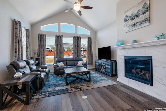 living room featuring a tile fireplace, ceiling fan, dark hardwood / wood-style flooring, and vaulted ceiling