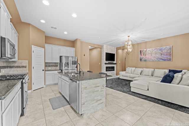 kitchen with appliances with stainless steel finishes, white cabinetry, a kitchen island with sink, and sink