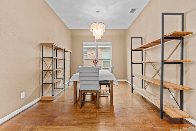 dining space featuring hardwood / wood-style floors and an inviting chandelier