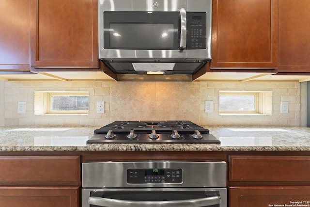 kitchen featuring light stone countertops, appliances with stainless steel finishes, and tasteful backsplash