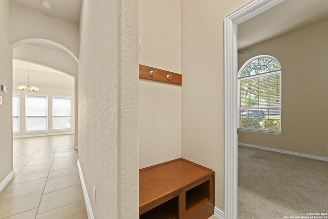 mudroom with light tile patterned floors and a notable chandelier