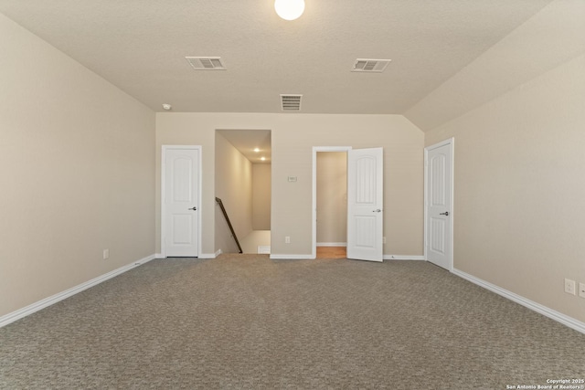 unfurnished bedroom with carpet floors, a textured ceiling, and vaulted ceiling