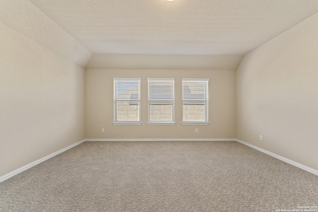 unfurnished room featuring a textured ceiling, carpet, and lofted ceiling