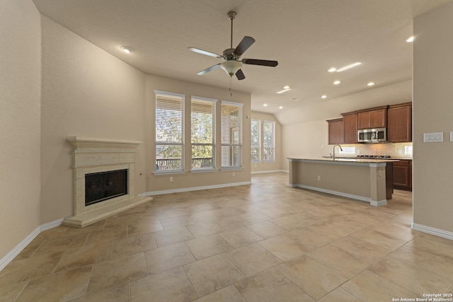 unfurnished living room with ceiling fan, sink, and a fireplace