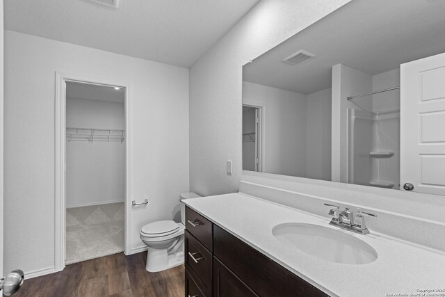 bathroom with a shower, vanity, hardwood / wood-style flooring, and toilet