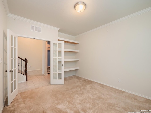 spare room with light colored carpet, crown molding, and french doors