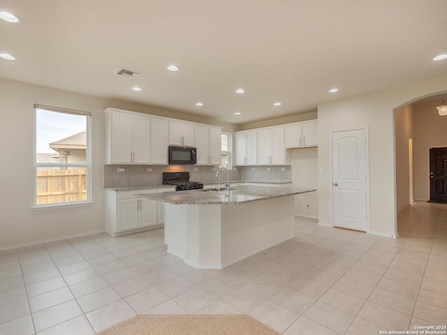 kitchen featuring black appliances, sink, white cabinetry, and an island with sink