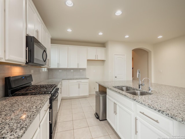 kitchen with light stone counters, sink, black appliances, light tile patterned floors, and white cabinets