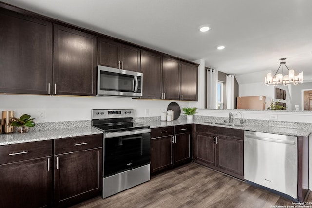 kitchen with dark brown cabinetry, sink, dark wood-type flooring, a notable chandelier, and appliances with stainless steel finishes