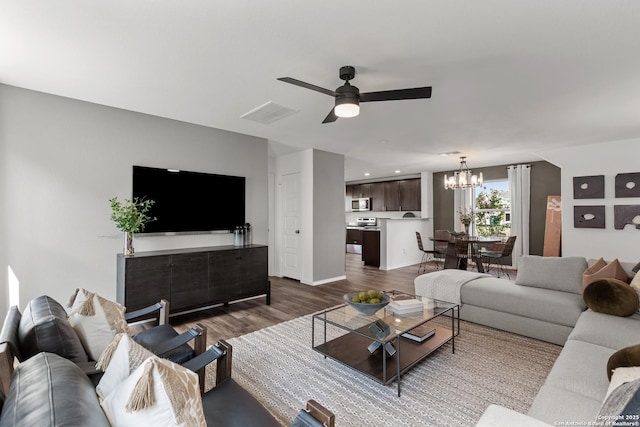 living room featuring ceiling fan with notable chandelier and dark hardwood / wood-style flooring