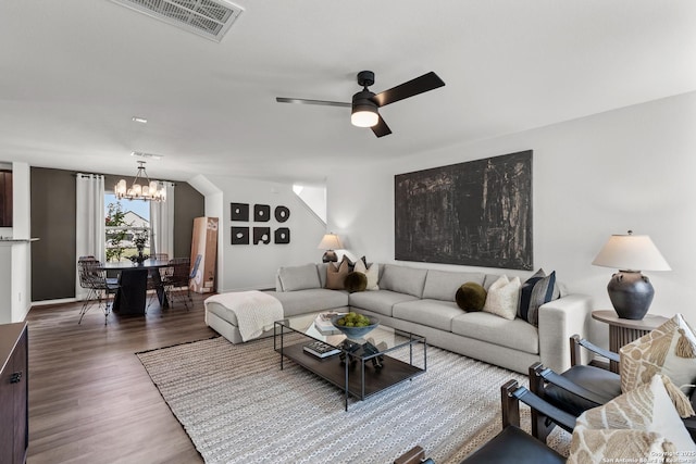 living room with ceiling fan with notable chandelier and dark hardwood / wood-style flooring