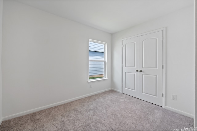 unfurnished bedroom with light colored carpet and a closet